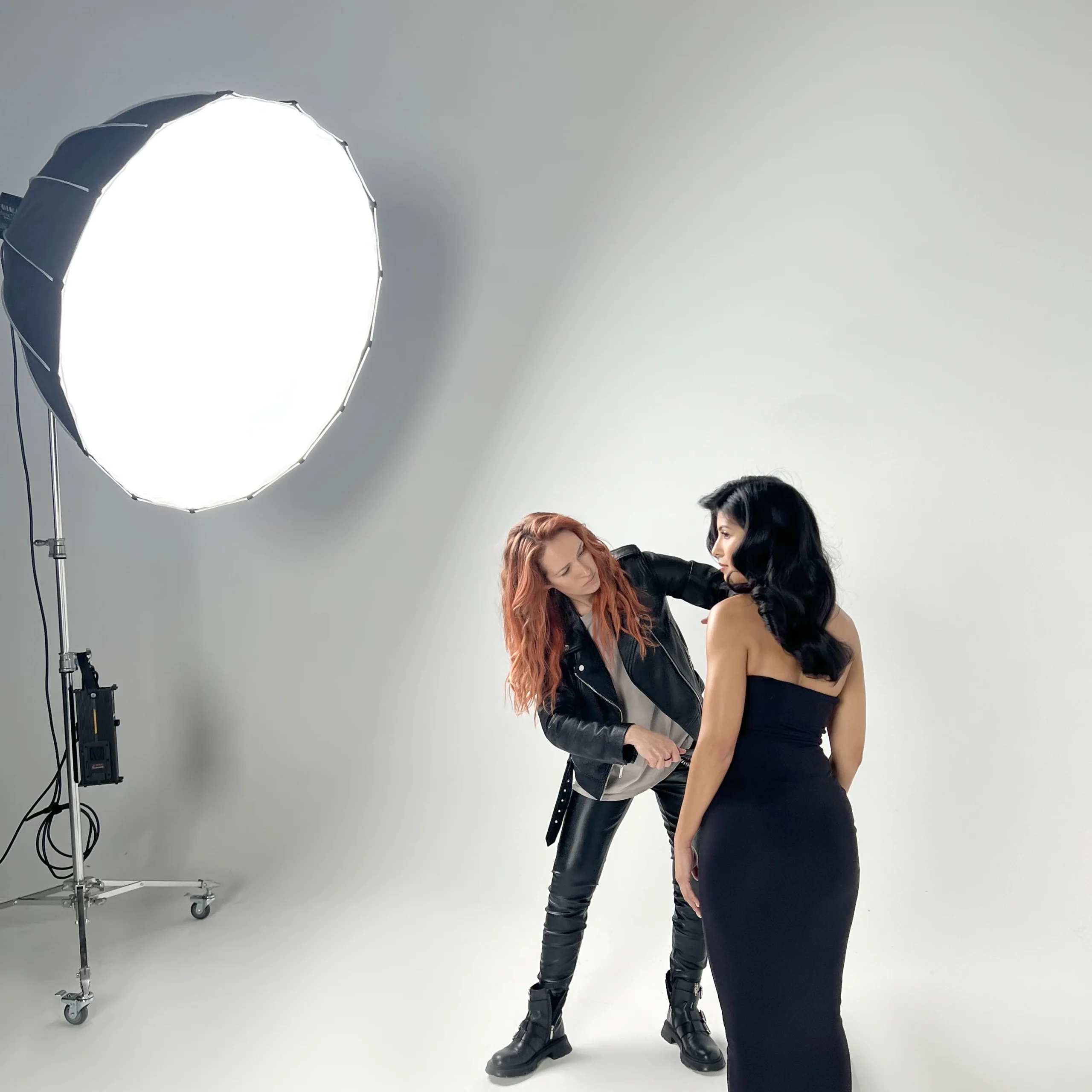 Hairstylist Yuliia adjusts model's hair during studio photo shoot