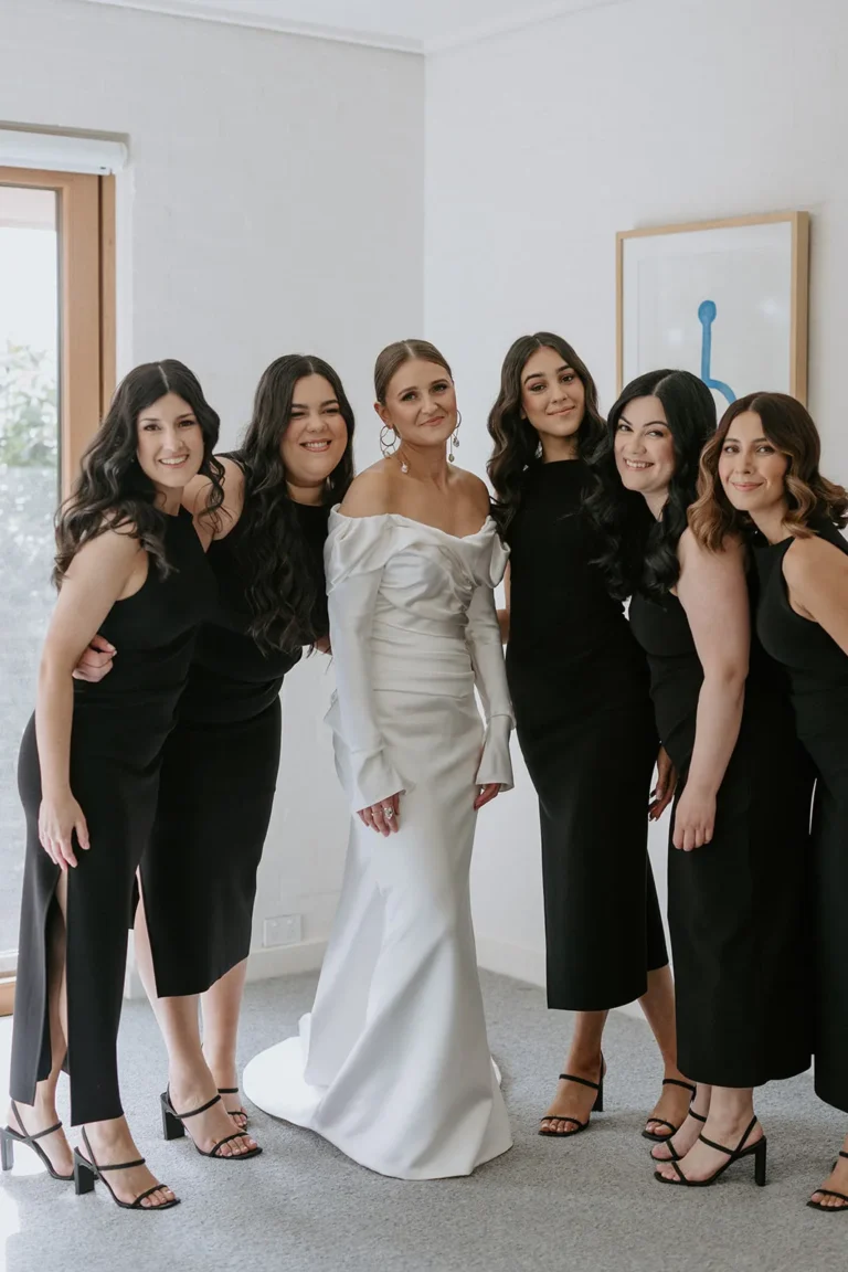 Group of women dressed for a wedding posing with the bride.