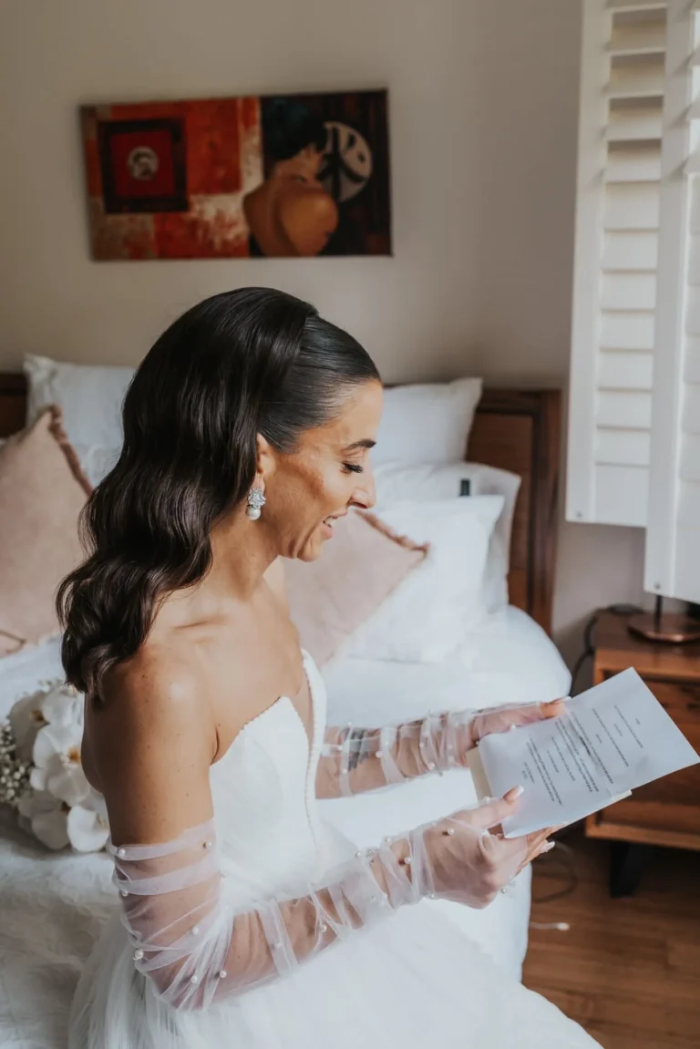 Bride reading a letter with soft curls and wedding gloves on.