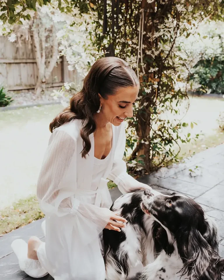 A bride with a beautiful hairstyle is petting a dog and smiling